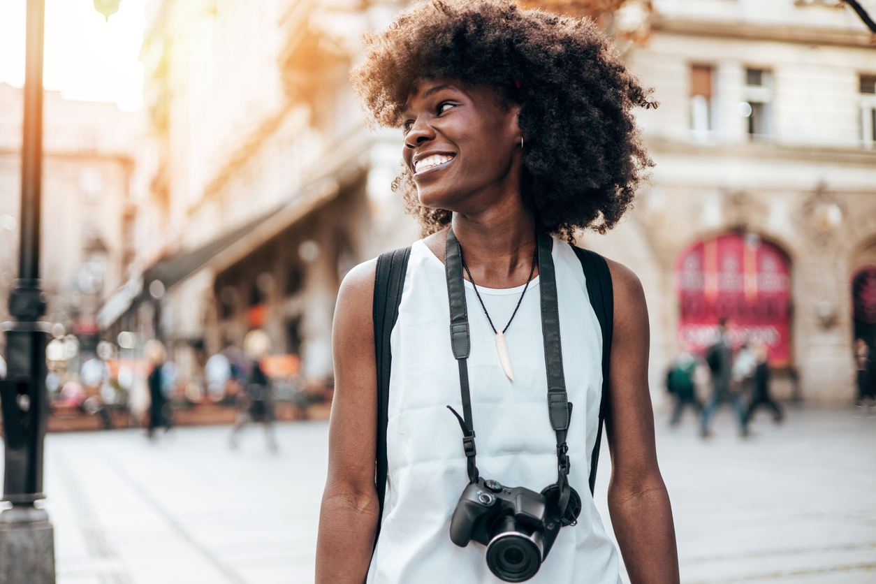 The image shows a young black woman exploring a new place to visualize activities to try in Costa Mesa.