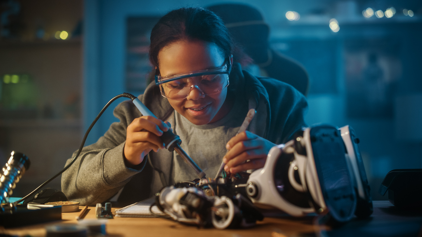 The image shows a girl working on a robot in her room to show women in STEM what the best materials to use in your robotics are.