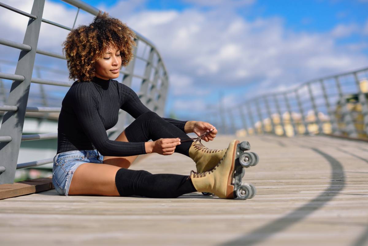 Woman sitting down and tying her roller skate laces.
