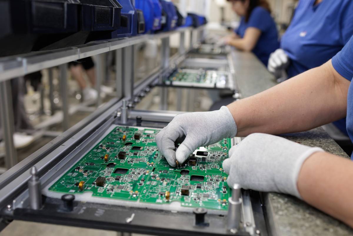 Gloved technician assembling PCB on modern SMT production line