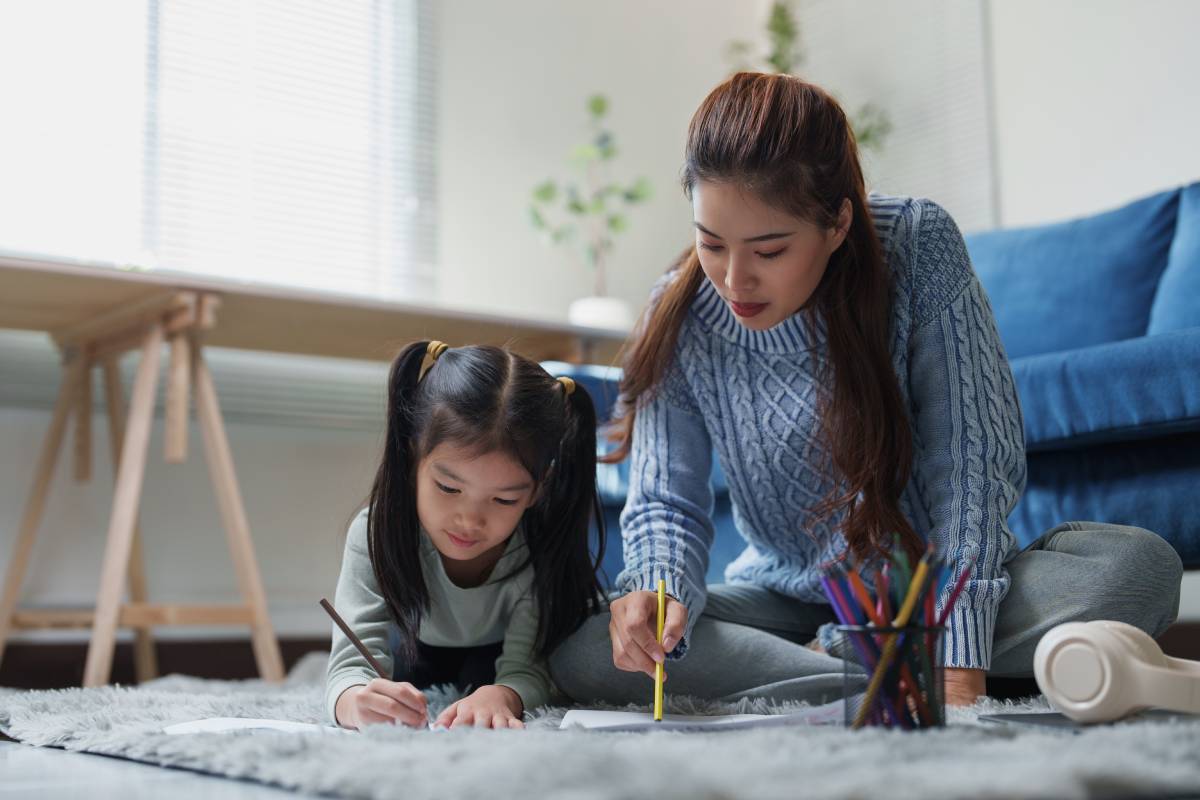 Mother and daughter lying on the floor drawing and coloring together
